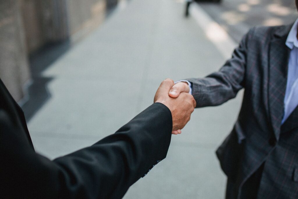 Two business owners shaking hands, the local partnership behind an earned backlink