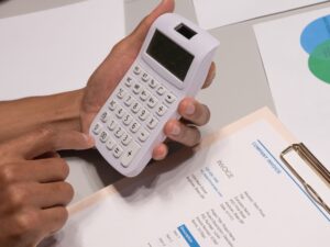 Hands using a calculator next to an invoice, pricing an HVAC service call