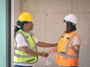 Two contractors in safety gear shaking hands after a job well done, the moment to ask for a review